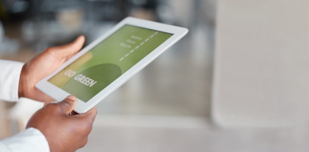 Hands holding a tablet showing a green sustainability graphic
