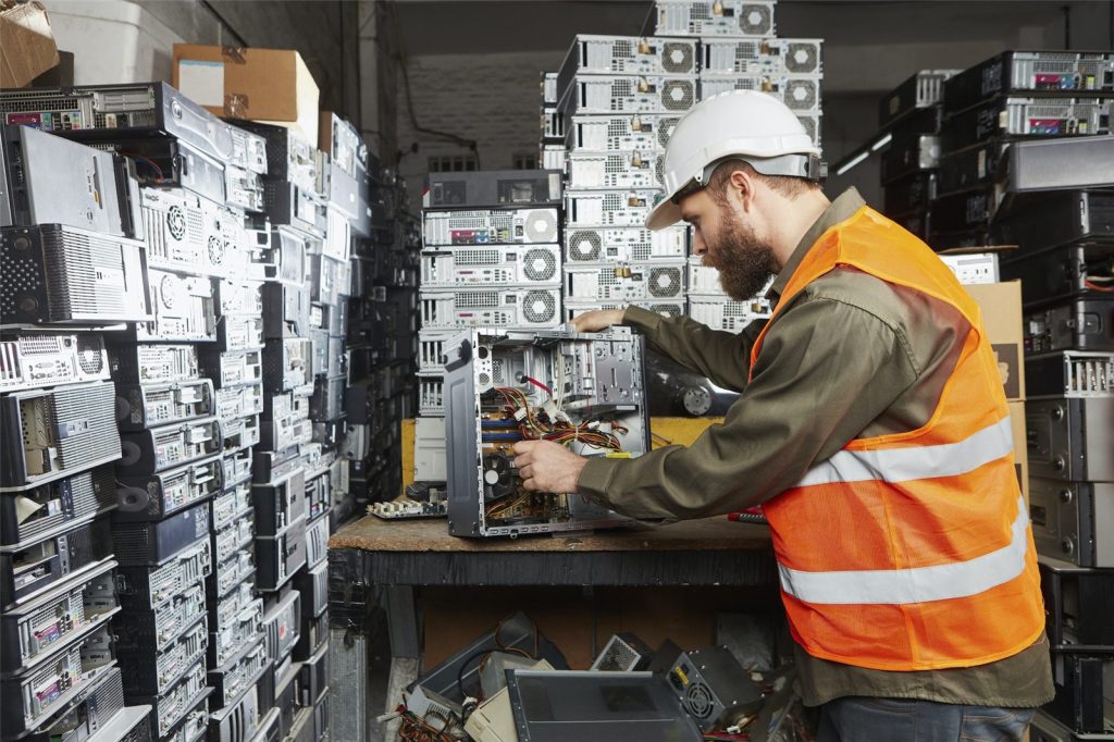 Worker in a computer recycling plant dismounting a desktop PC